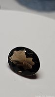 Close-up photo of oval cut natural smokey quartz gemstone showing clear faceted surface and color.
