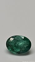 Oval cut 1 carat emerald showing rich green color and polished facets with some visible inclusions.