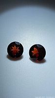 Two round faceted pyrope garnet stones showing deep red color and clarity from the top side.