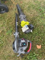 Two Ryobi gas powered jet fan blowers and one Craftsman gas powered blower on grass, aerial view.