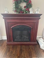 Front view of Twin Star Home electric fireplace model 23EF010GRA with wooden mantel and glass front showing simulated logs inside.