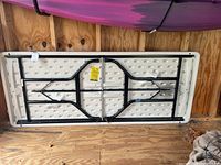 Folded folding table showing underside with black metal legs and resin top.