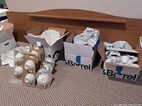 Boxes containing Lenox Mansfield china pieces wrapped in packing paper.