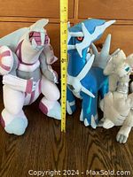 Three Pokemon plush: Palkia, Dialga, and White Kyurem, shown standing next to a tape measure showing approx 15-17 inches tall.