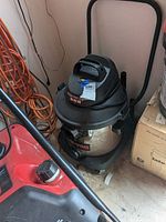 Photo showing full view of Superior 8 gallon shop vac with stainless steel tank on floor with surrounding items.
