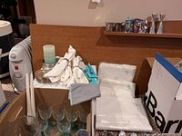 White folded linen placemats, cloth napkins, metal napkin rings, candles on plate, and boxed wine glasses