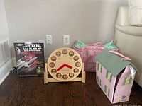 Front view of the three main items: Star Wars X-Wing model kit box, Pottery Barn Kids wooden clock, two soft fabric doll houses (castle and house).