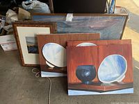 Five art prints leaning against a surface, including framed and unframed prints. Shows overall contents of the lot.