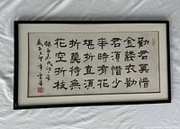 Full view of the framed Chinese calligraphy piece showing the entire artwork with black wood frame and signature stamps on the paper.
