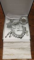 Jewelry set consisting of necklace, earrings, ring, hair combs, and compact mirror displayed inside Fifth Avenue Collections box with tissue paper