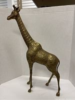 Full side view of brass giraffe sculpture showing shape and embossed pattern.