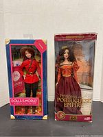 Both Barbie dolls in original packaging, RCMP Canada Barbie in red uniform and Princess of the Portuguese Empire in burgundy and gold gown.