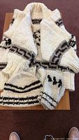 Full lot photo showing the sweater, mitts, and toque folded on table