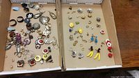 Two trays of earrings showing a wide variety of styles including vintage and clip-ons, floral and novelty shapes