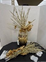 Large ribbed gold vase with gold branch lights in and around it, displayed in white background