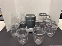 Front view of Nutribullet blender base and various blending jars and cups arranged in front.