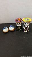 Full view of the four salt and pepper shakers in the set: two blue and white bird-shaped pieces and two colorful human figurines with hats