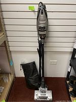 Full view of Shark Rocket Ultralight Pro vacuum standing upright with power cord and a black storage bag attached.