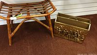 Wicker stool with brass paper holder beside it on carpeted floor, showing size and design details.