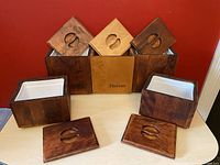 Six wooden canisters with lids removed showing white plastic inserts inside four canisters; front Biscuits canister lighter wood color; lids have carved coffee bean handles.