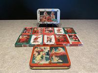 Overview of all playing card decks and two collectible Coca-Cola tins arranged on flat surface.