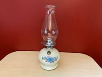 Full view of the Lamplight Farms vintage oil lamp with white cased glass base and blue flowers, clear glass chimney.