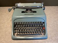 Front view of the olive green Underwood Olivetti Studio 44 typewriter showing keyboard and carriage return lever.