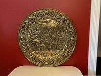 Front view of the brass plate showing detailed embossed tavern scene and ornate border