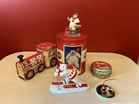 Photo showing full lot with Coca-Cola metal train, large red tin with polar bear, skiing polar bear figurine, small round lid, and pin.