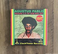 Front view of the sealed Agustus Pablo reggae 3x10 inch dub box set on a wooden surface showing colorful packaging and label indicating color vinyl.