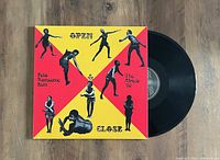 Photo showing the vibrant cover art with red and yellow background featuring multiple black silhouettes of Fela Kuti dancing, and the partially visible black vinyl record.