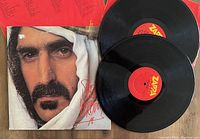 Photo showing the album cover featuring a close-up of Frank Zappa, the two black vinyl records with red labels laid on top of the album jacket.