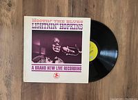 Photo of Lightnin' Hopkins Hootin' The Blues vinyl record with jacket layed on wood floor showing front cover and vinyl partially removed.