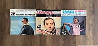 Photo shows three Charles Aznavour EP vinyl record covers laid side by side displaying front cover art and titles