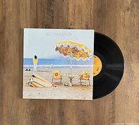 Photo showing the vinyl record partially out of the On The Beach album cover jacket, lying on a wood surface.