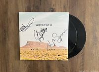 Autographed front cover of The Trews Wanderer album gatefold jacket with two black vinyl LPs partially visible.