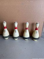 Four Brunswick Score King bowling pins standing upright, showing overall wear and paint chipping.