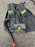 Photo showing black Aqua Lung Rocket fins with logo on top surface, US Divers mask with blue trim around lenses and black snorkel with orange tip positioned in front.