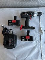 Craftsman cordless drill driver with two batteries and charger laid out on white surface