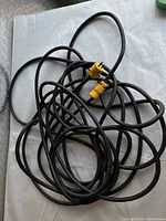 Full view of the coiled heavy duty black cable with yellow plug and connector ends.