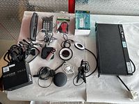 Top-down view of mixed electronic lot including Power Supply, WiFi Extender, smart devices, chargers, cables, and LED lamp.
