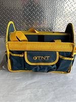 Front view showing the OTNT logo flap pocket and multiple external pockets with yellow edging.