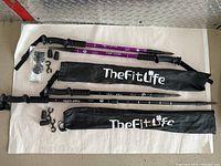 Two telescopic walking sticks laid out with their carrying bags and accessories on a white surface.