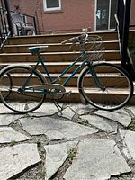 Side view showing the entire CCM vintage ladies bike with basket, chain guard, kickstand and blue frame.