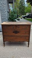 Front view of the antique 4 drawer wooden dresser showing two small top drawers and two large bottom drawers with ornate wood detailing and round metal pulls.