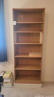 Front view of the full tall MDF bookshelf showing five shelves with dividers and natural wood finish.
