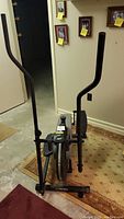 Front view of the Orbitrek elliptical machine showing dual vertical handlebars, foot pedals, and control console area.