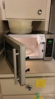 Hamilton Beach microwave oven with open door and two plastic bowls on top
