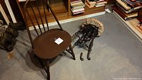 Wooden chair and disassembled vintage piano stool parts on floor, showing condition and details including brass dolphin feet