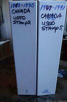 Two white slipcase binders labeled 1880-1970 and 1987-1991 Canada used stamps.